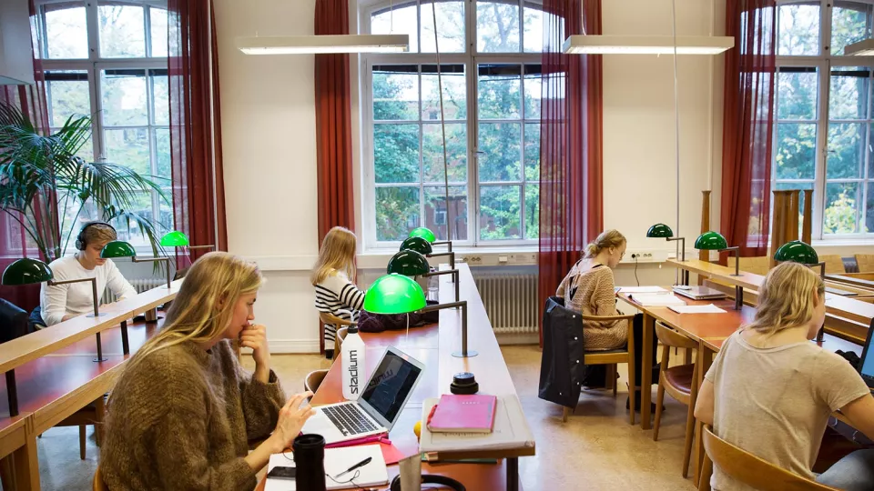 Students study at desks with green lamp fixtures. Photographer Johan Bävman.