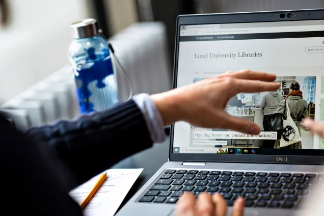 An open laptop. Hands pointing at the screen. 