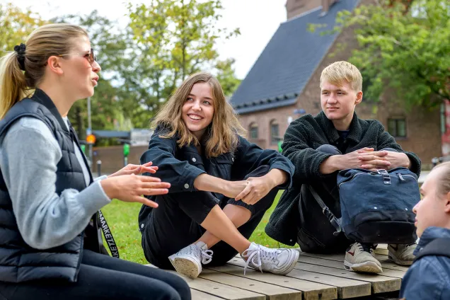 Tre studenter lyssnar på en kvinna. Fotograf Kennet Ruona.