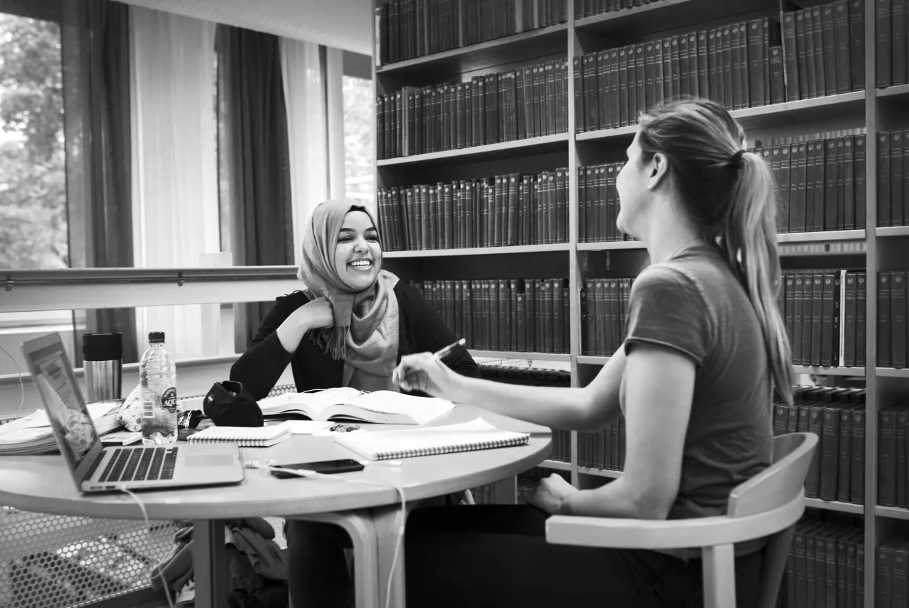 Två glada studenter studerar tillsammans på Universitetsbiblioteket. Fotograf Johan Bävman.