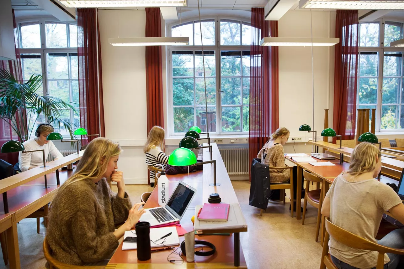 Studenter studerar vid bänkar med gröna lampor. Fotograf Johan Bävman.